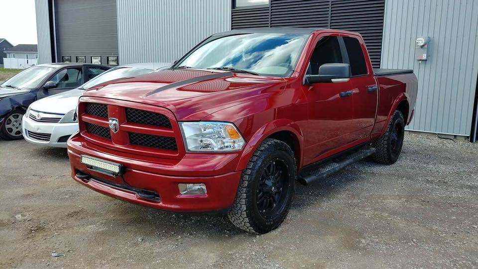 Panneaux et pare‑chocs en attente de réparation dans un atelier de carrosserie à Alma