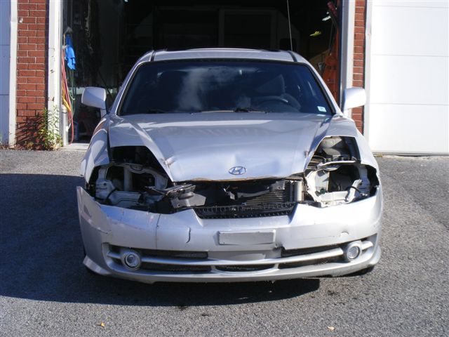 Panneaux et pare‑chocs en attente de réparation dans un atelier de carrosserie à Candiac 