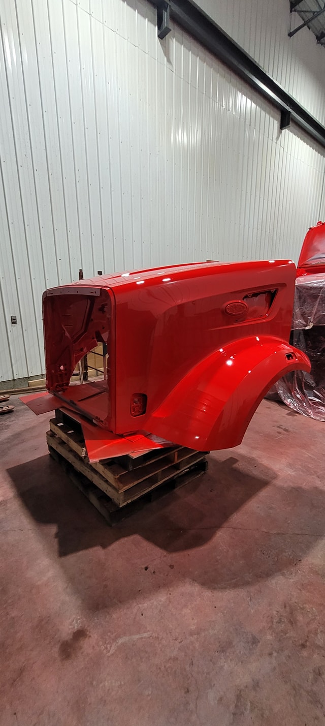 Panneaux et pare‑chocs en attente de réparation dans un atelier de carrosserie à Montmagny