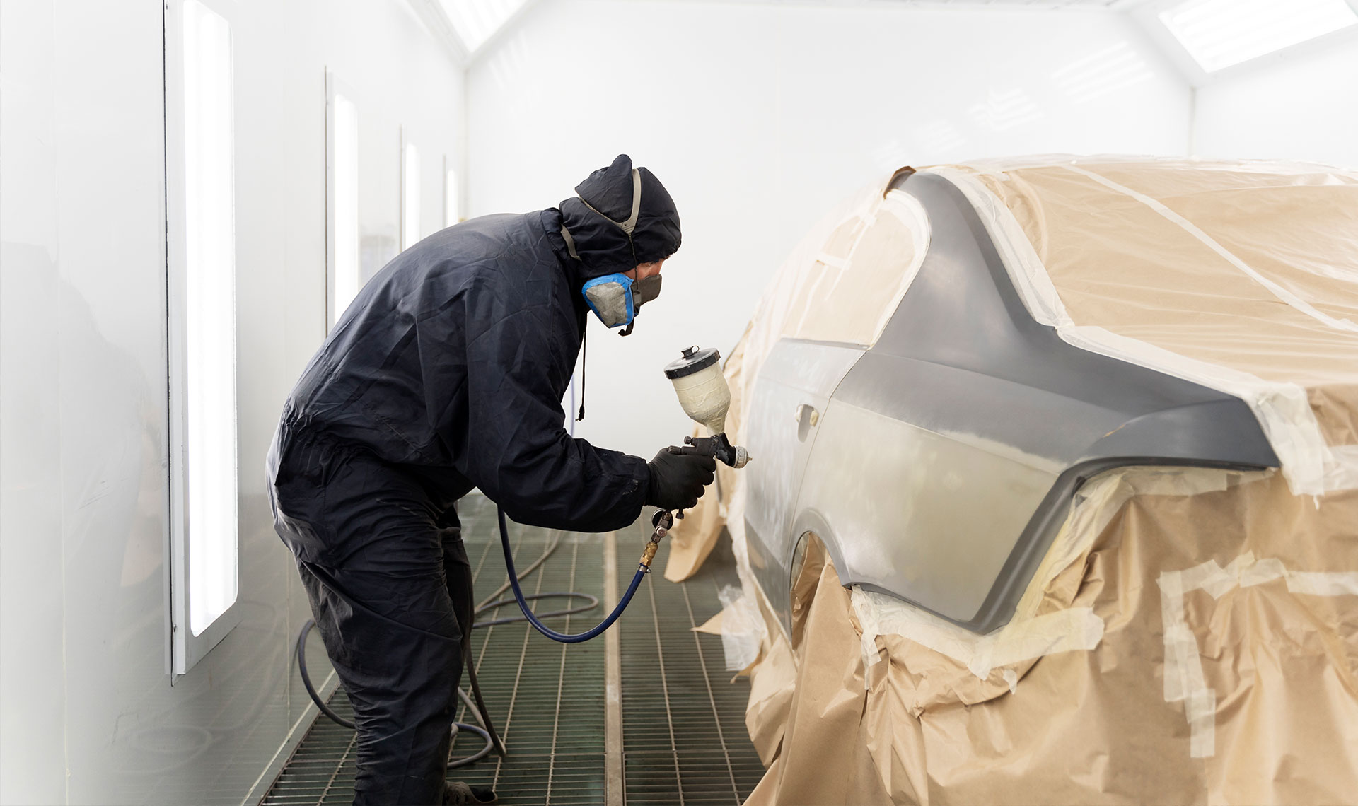 Carrossier ponçant un panneau de carrosserie dans un atelier à Saint-Hyacinthe