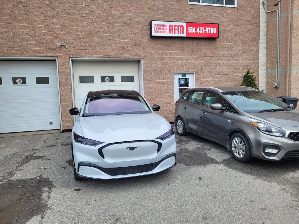 Carrossier ponçant un panneau de carrosserie dans un atelier à Vaudreuil-Dorion