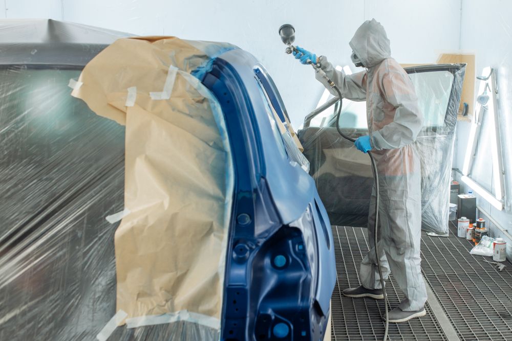 Carrossier ponçant un panneau de carrosserie dans un atelier dans le Nord-du-Québec